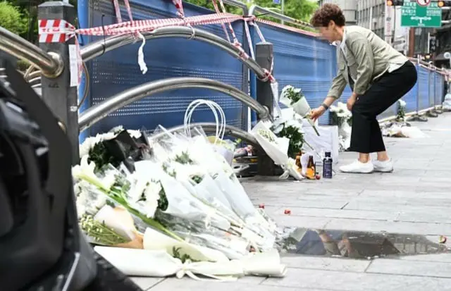 市庁近くの事故現場で、犠牲者を追悼して献花する市民